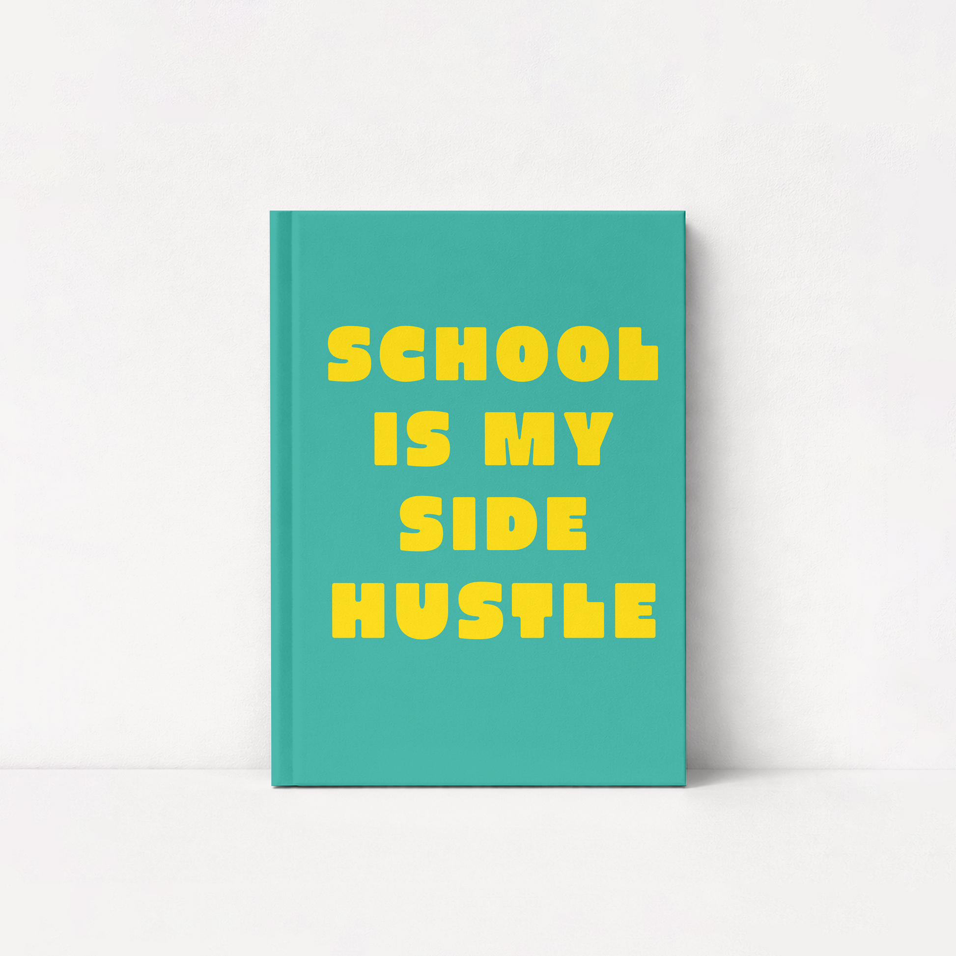 A teal hardcover notebook with bold yellow text reading 'SCHOOL IS MY SIDE HUSTLE' on a clean white background.