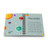 A personalized spiral-bound children's notebook with an outer space theme, featuring colorful planets, rockets, stars, and a custom name 'Alexander' with alphabet letters on the light blue cover, shown on a white background.