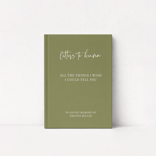 An olive green hardcover journal standing upright against a white background. The front cover features white text reading 'letters to heaven' in a cursive font, followed by 'ALL THE THINGS I WISH I COULD TELLYOU' and 'IN LOVING MEMORY OF AMANDA MILLER' in a serif font.