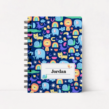 A spiral-bound notebook with a dark blue cover featuring a colorful cartoon safari pattern of lions, elephants, rainbows, and snakes. A white label on the front reads 'Jordan'.