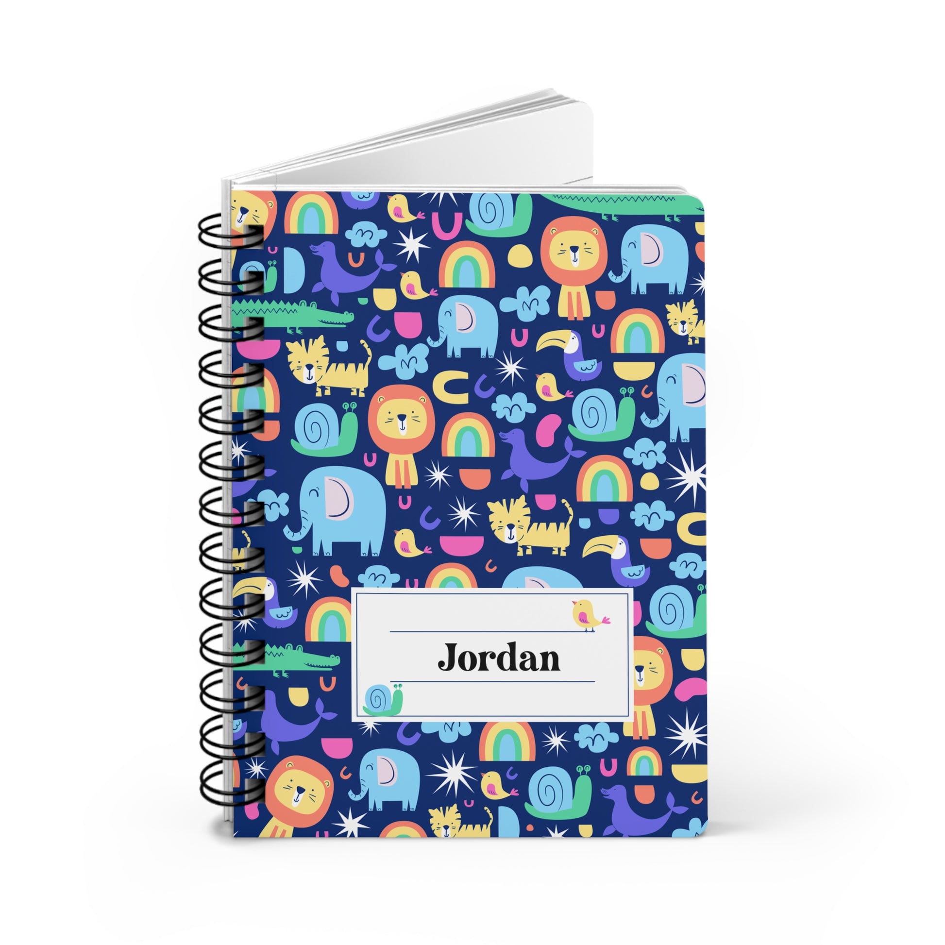 A spiral-bound notebook with a colorful cartoon animal and rainbow pattern on a dark blue cover, featuring a white label that reads 'Jordan'.