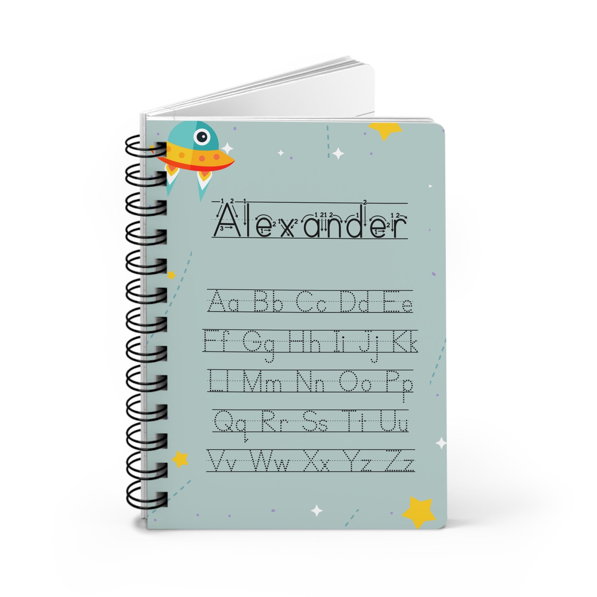 A personalized spiral-bound notebook with a light blue cover featuring the name 'Alexander' and the alphabet in dotted lines, decorated with a cartoon rocket and stars.