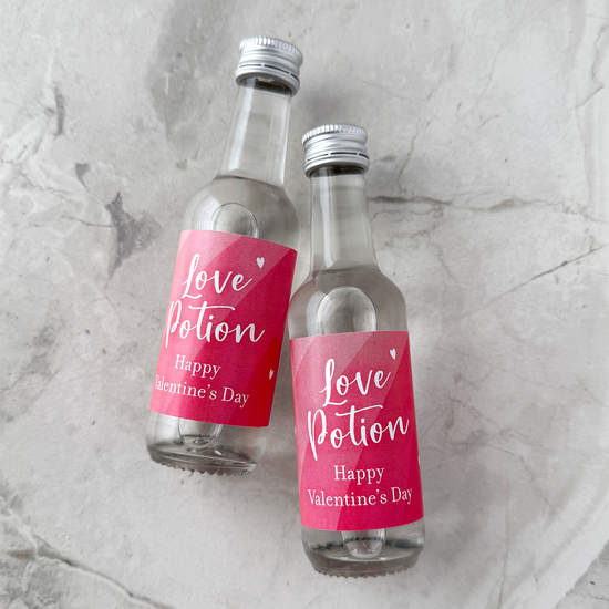 Happy Valentines Day Favors Two small bottles with 'Love Potion' labels on a gray marble surface