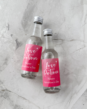 Happy Valentines Day Favors Two small bottles with 'Love Potion' labels on a gray marble surface