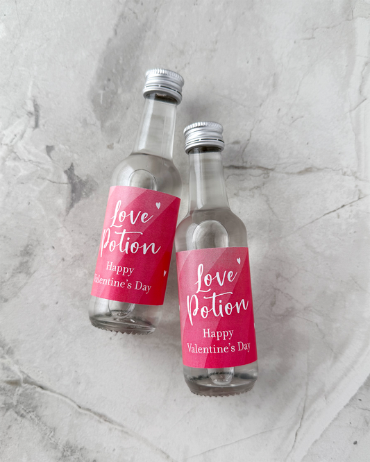 Happy Valentines Day Favors Two small bottles with 'Love Potion' labels on a gray marble surface