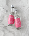 Two small glass bottles with pink 'Love Potion' labels on a gray marble surface.